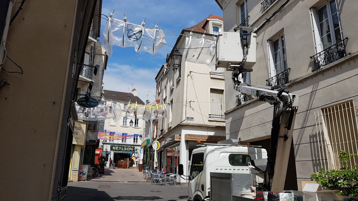 Christophe Alzetto prépare l'installation Cadavre Exquis, à l'aide des ouvriers de la ville et d'une nacelle. On voit l'accrochage en hauteur et ses difficultés